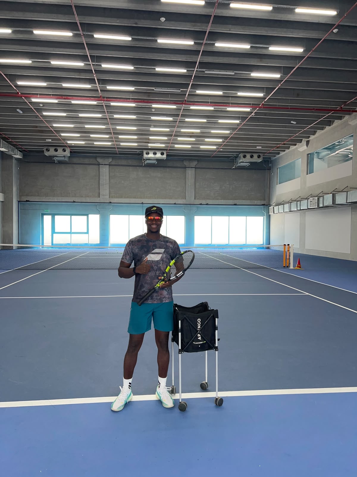 Coach Frank on an indoor hard court in Kuwait with a ball hopper